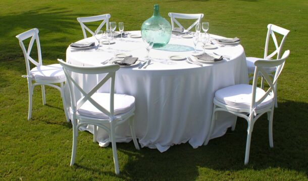 mesa redonda con mantel blanco y silla plegable de madera blanca montaje de vajilla