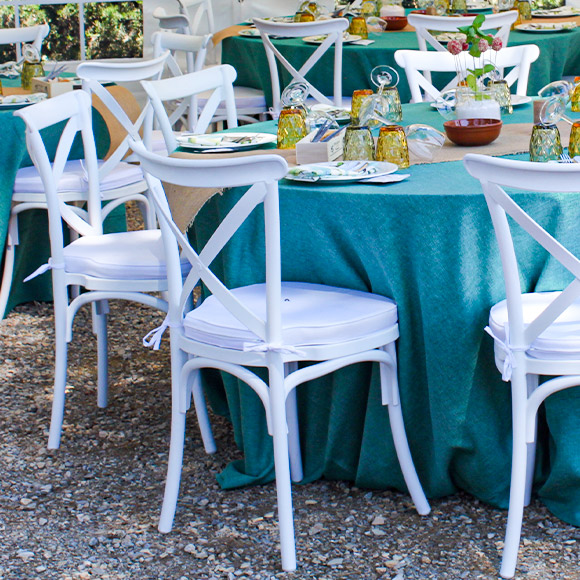 mesa redonda con mantel verde y sillas crossback blancas