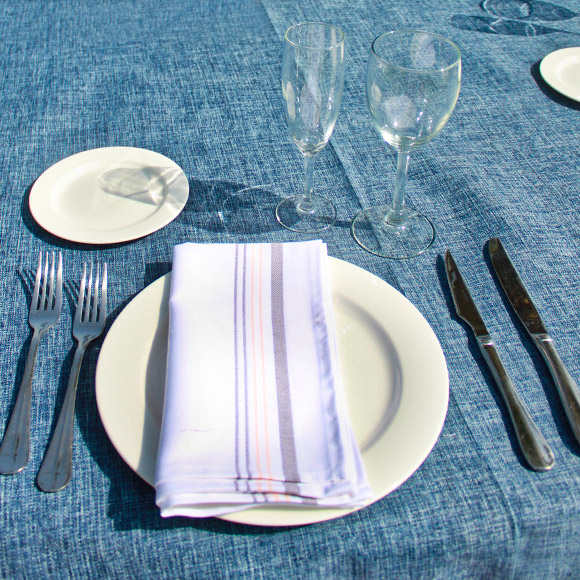 presentación de plato platos blancos con copas de cristal servilleta a rayas y cubiertos